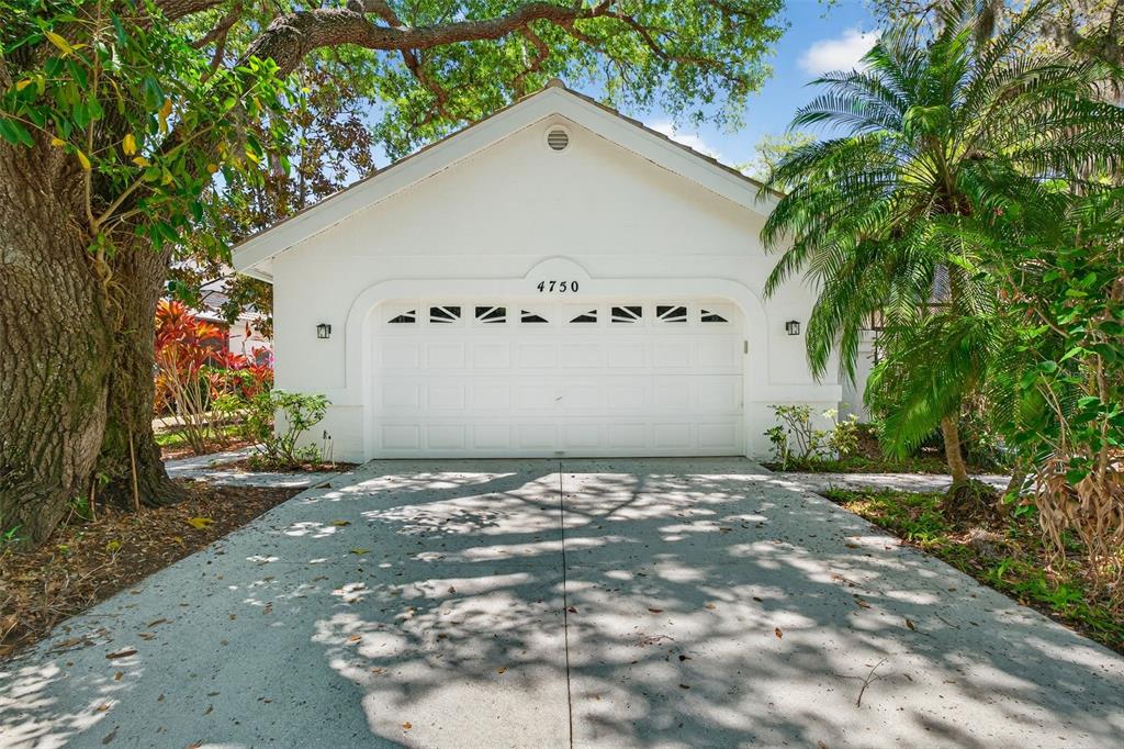 A white detached garage with a concrete driveway sits under large trees — 4750 TIVOLI AVENUE, SARASOTA, FL