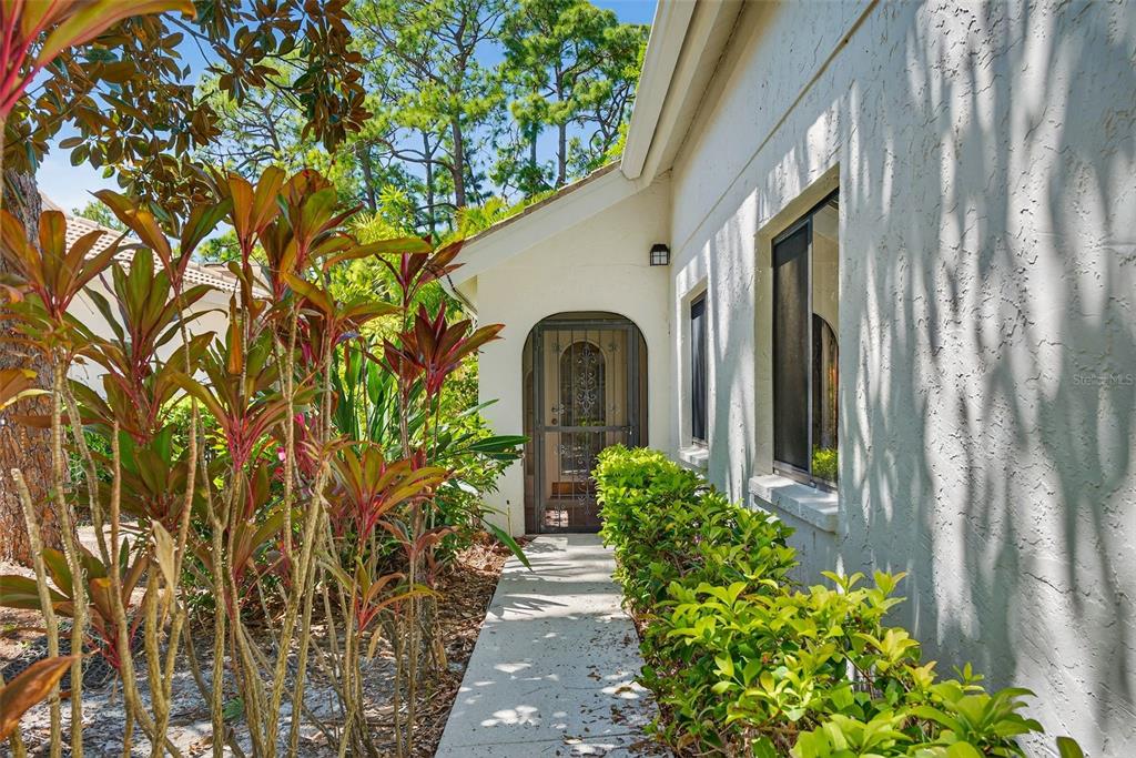 A concrete walkway leads to an arched front door with a metal security screen — 4750 TIVOLI AVENUE, SARASOTA, FL