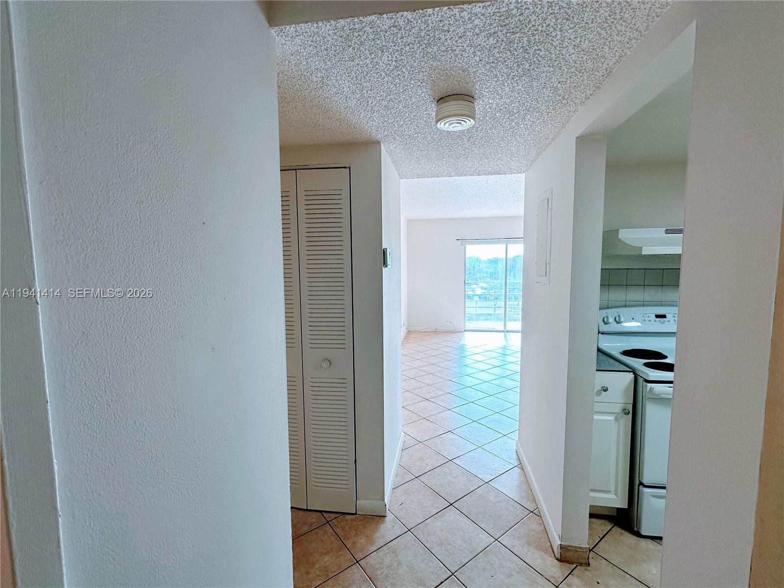A view from a hallway looking toward a living area with tile floors and balcony — 4364 NW 9th Ave # 3F, Deerfield Beach FL 33064, DEERFIELD BEACH, FL