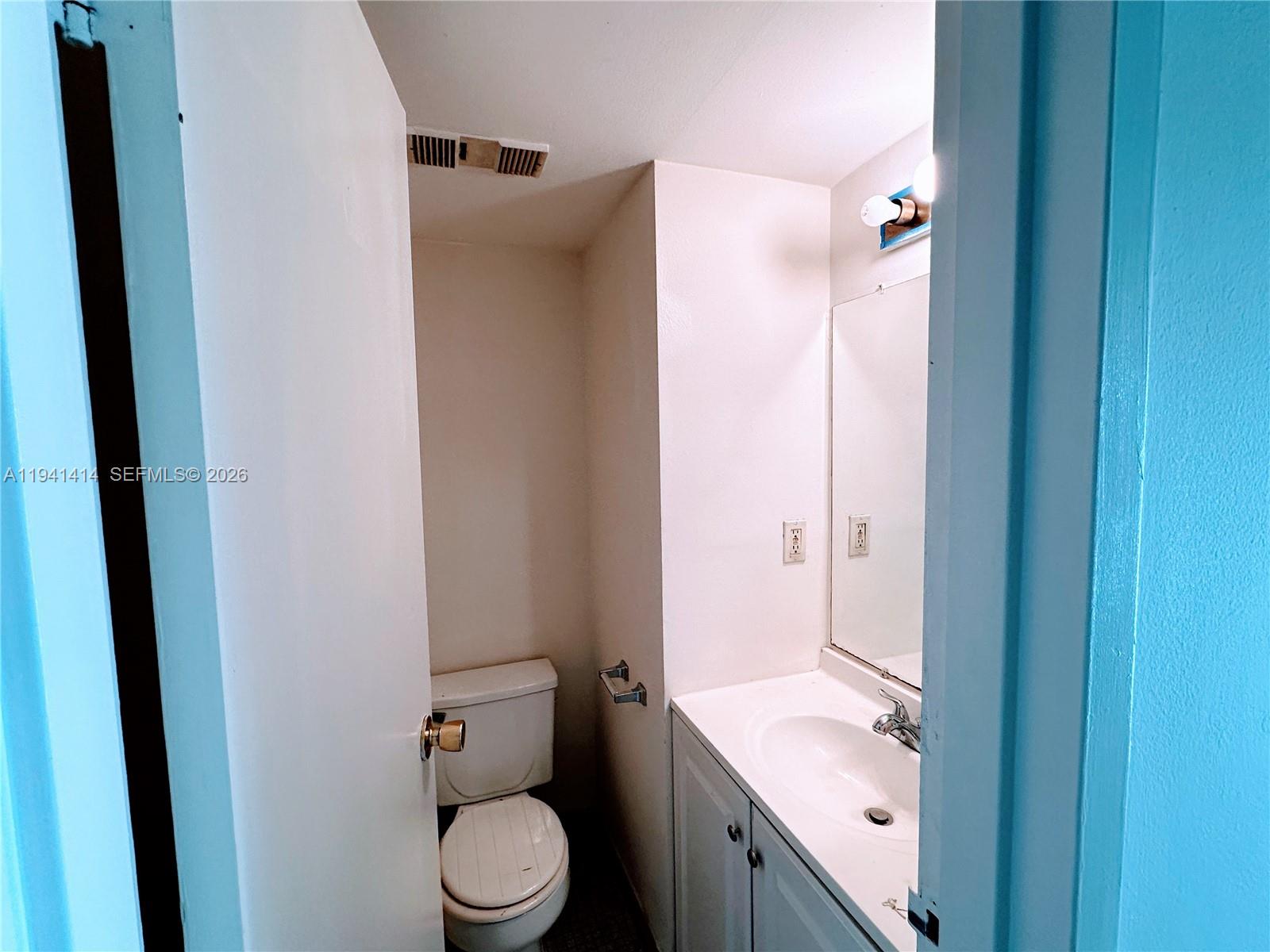 A small bathroom features a white vanity, a mirror, and a toilet in a corner — 4364 NW 9th Ave # 3F, Deerfield Beach FL 33064, DEERFIELD BEACH, FL