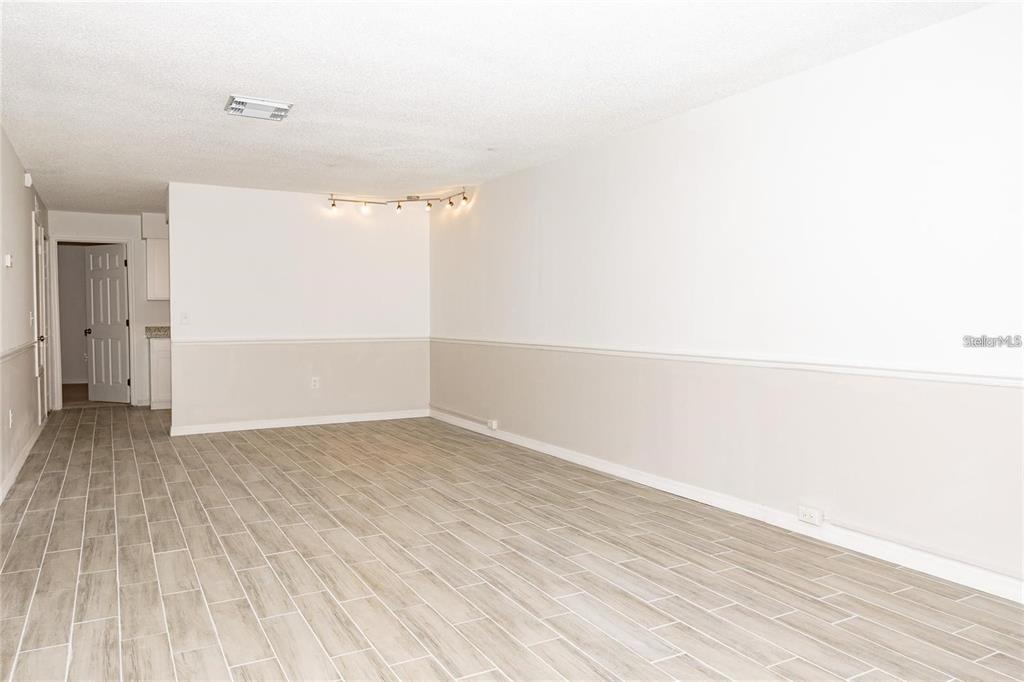 An empty room features light-colored wood-look tile flooring and walls with a chair rail — 1267 WOODMAN WAY, ORLANDO, FL