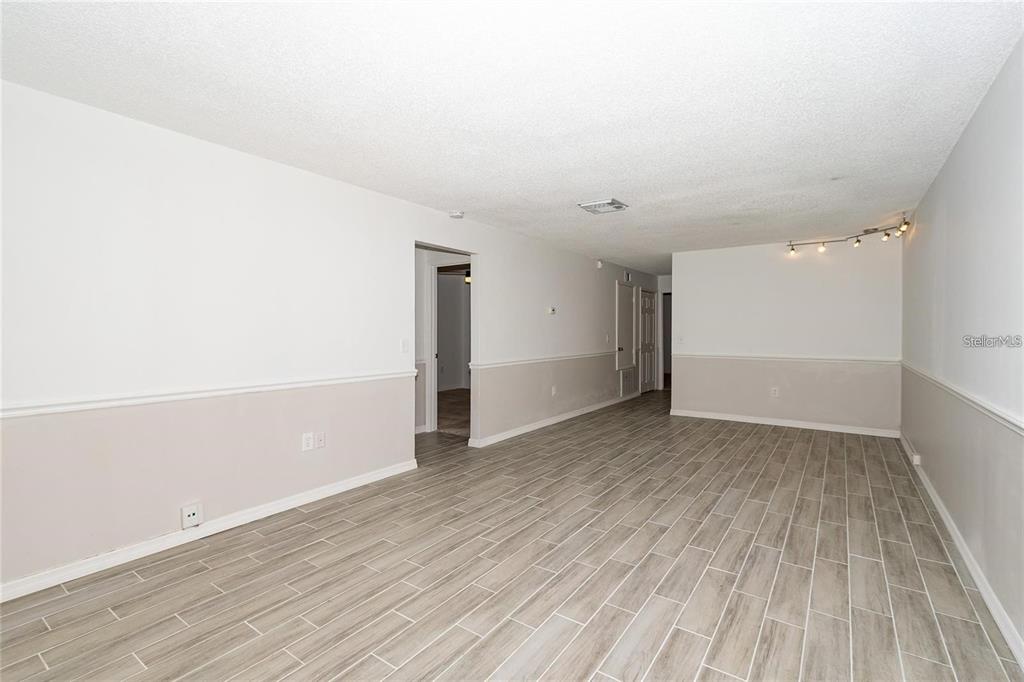 An empty room features light-colored wood-look tile flooring and two-tone walls with chair rail molding — 1267 WOODMAN WAY, ORLANDO, FL
