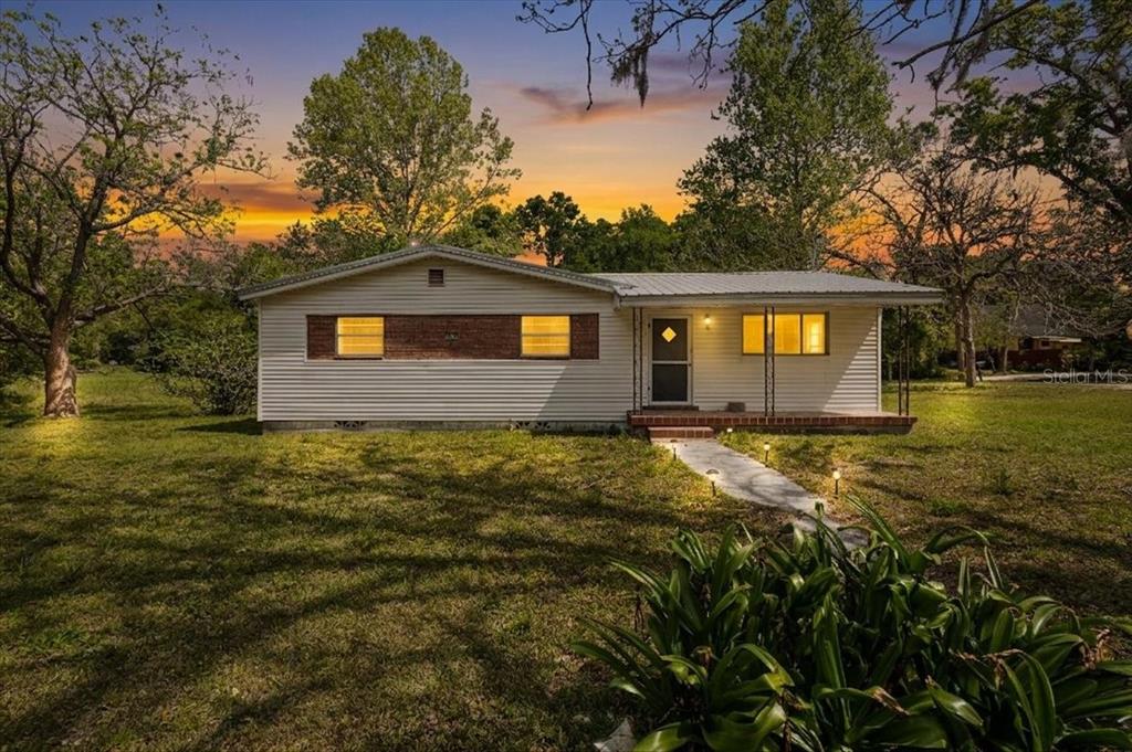 A single-story house with light siding and a brick accent wall sits on a lawn — 23832 NW 183RD ROAD, HIGH SPRINGS, FL