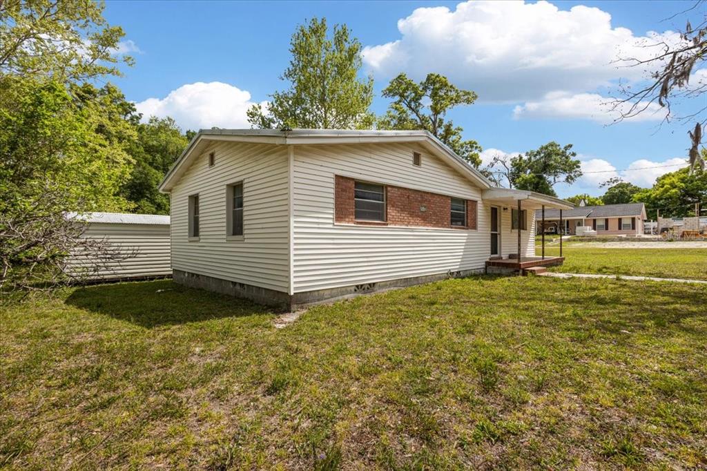 A single-story house with beige siding and a brick accent wall stands on a grassy lot — 23832 NW 183RD ROAD, HIGH SPRINGS, FL