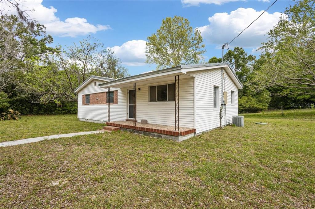 A single-story house with white vinyl siding and a front porch sits on a lawn — 23832 NW 183RD ROAD, HIGH SPRINGS, FL