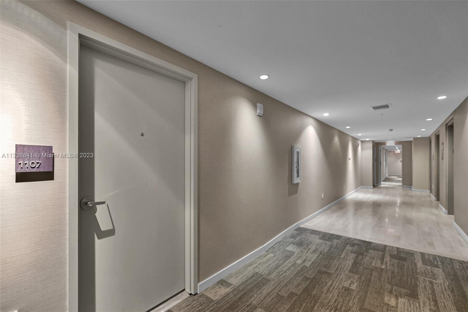 A hallway features a door labeled 1107, recessed ceiling lights, and a mix of carpeted and tiled flooring — 1010 SW 2nd Avenue # 1107, Miami FL 33130, MIAMI, FL
