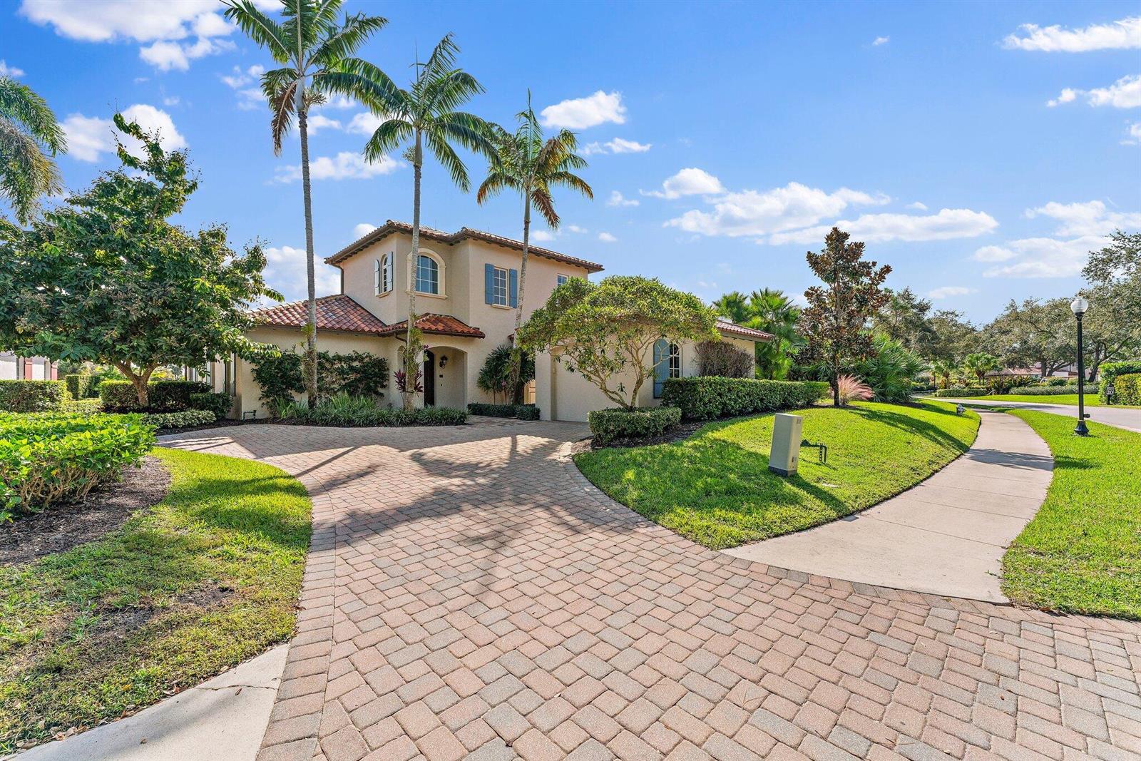 A two-story stucco house with a tiled roof and a paved driveway sits outdoors — 611 White Pelican Way, Jupiter FL 33477, JUPITER, FL