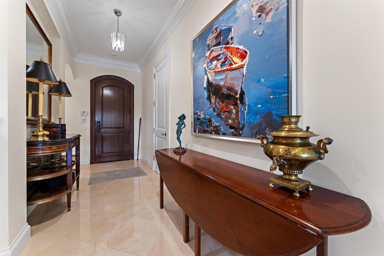 A foyer features a dark wood door, marble floors, a console table, and a large painting — 611 White Pelican Way, Jupiter FL 33477, JUPITER, FL