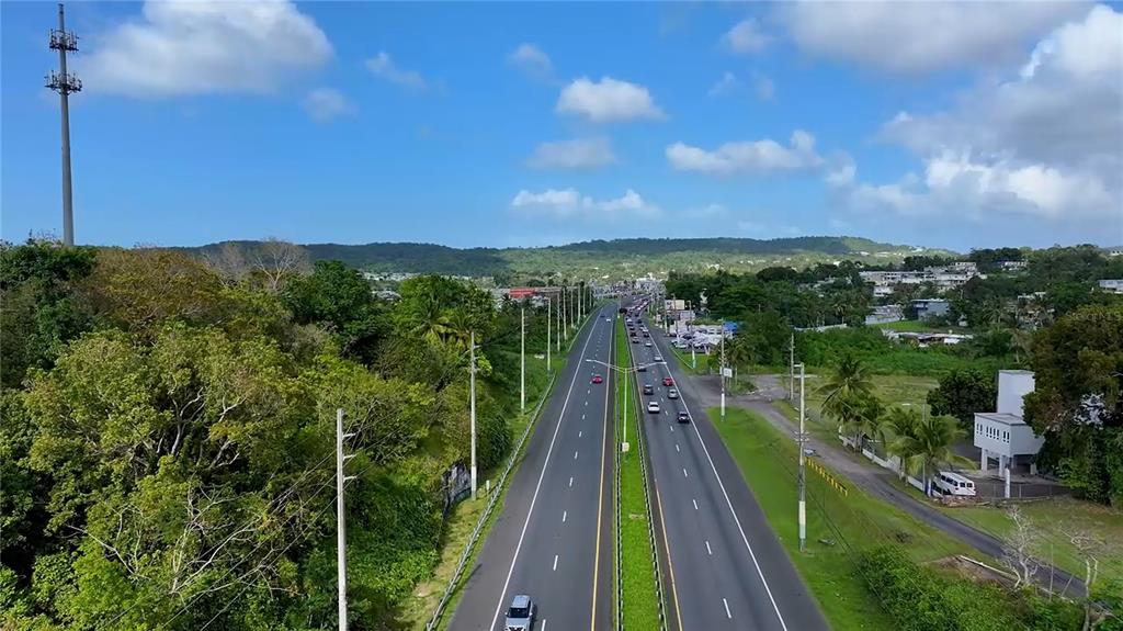 An aerial view shows a multi-lane highway stretching through a lush, green landscape — PR-3 KM 28.5 ZARZAL WARD, RIO GRANDE, PR