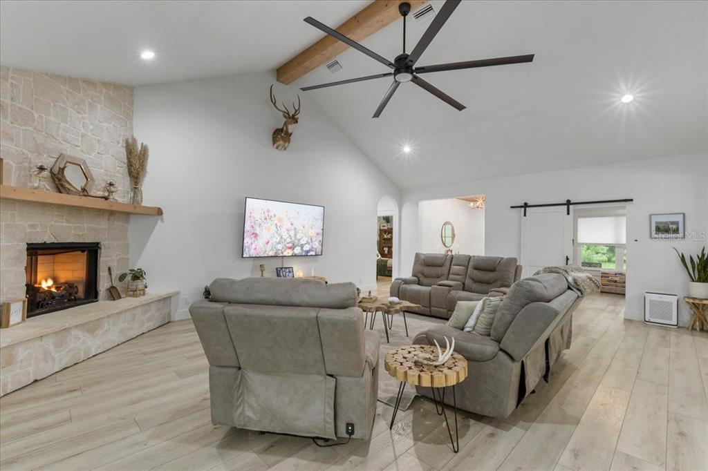 A living room features a stone fireplace, vaulted ceiling with a beam, and gray recliners — 9061 KATHERINE WAY, FANNING SPRINGS, FL