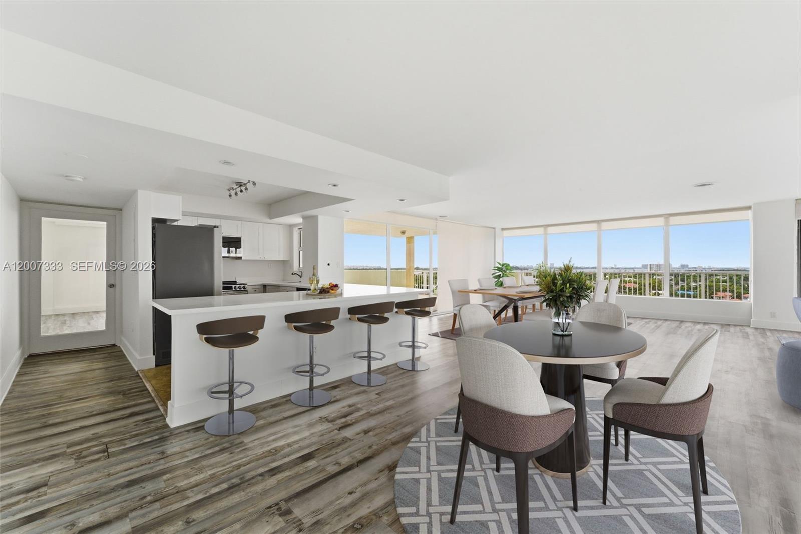 An open-concept kitchen and dining area features a breakfast bar, wood-look flooring, and floor-to-ceiling windows — 2000 NE 135th St PH, North Miami FL 33181, NORTH MIAMI, FL