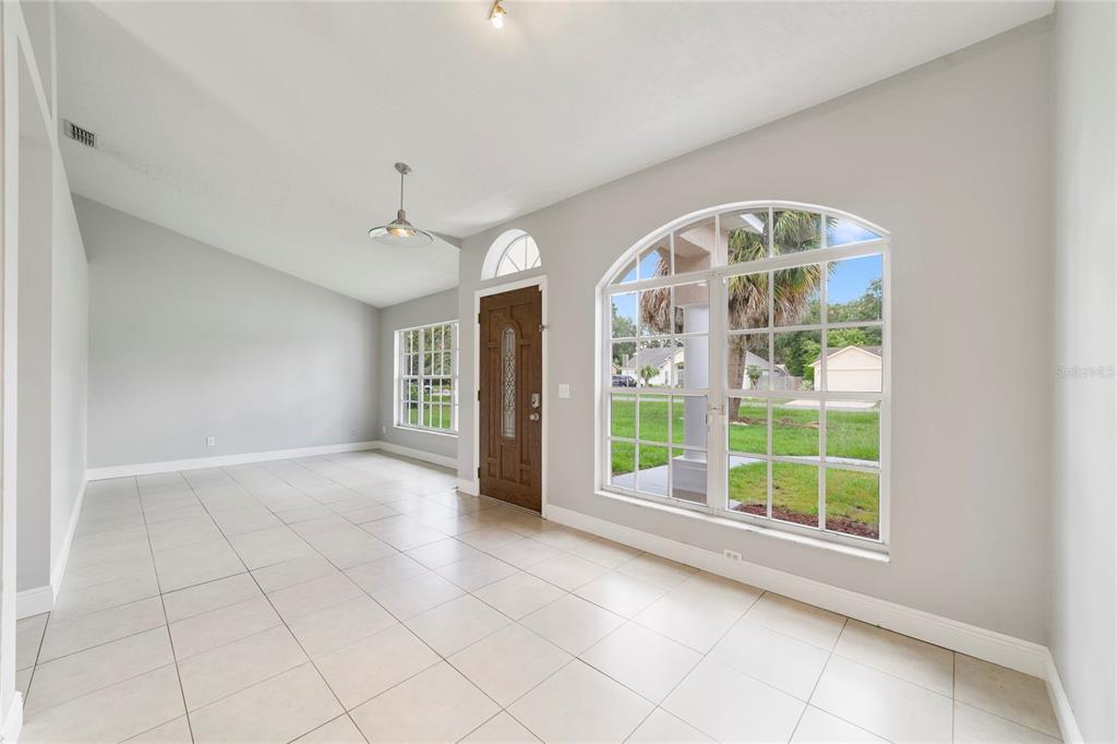An empty room with light tile flooring, a brown front door, and large arched windows — 309 WILD FORREST DRIVE, DAVENPORT, FL