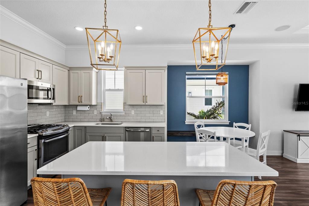 A kitchen with a large white island, gray cabinets, and a blue dining nook — 11213 MOULTRIE PLACE, TAMPA, FL