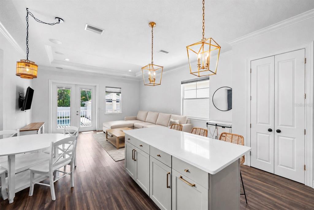 A bright, open-concept kitchen and living area features a white island, pendant lighting, and flooring — 11213 MOULTRIE PLACE, TAMPA, FL