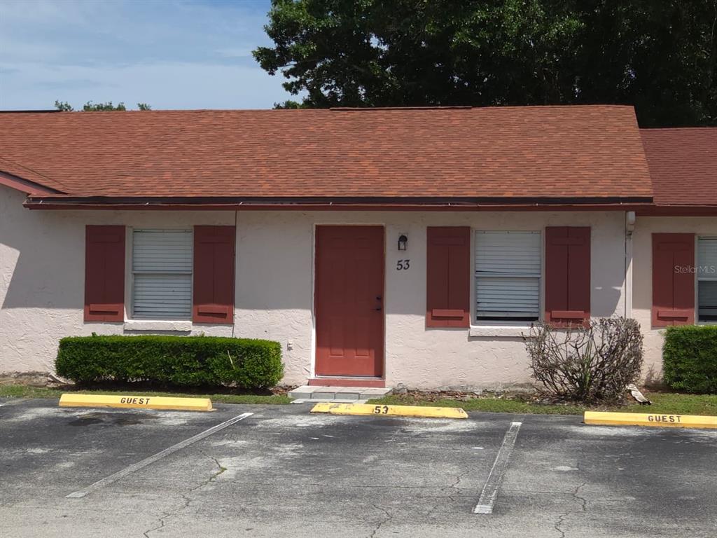 A single-story building exterior features a red door, red shutters, and designated guest parking spaces — 53 W MARBRISA WAY, KISSIMMEE, FL