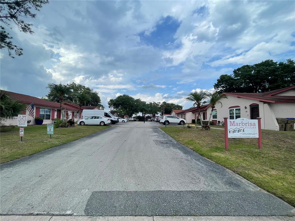A view of the entrance to the Marbrisa Villas complex with parked cars and landscaping — 53 W MARBRISA WAY, KISSIMMEE, FL