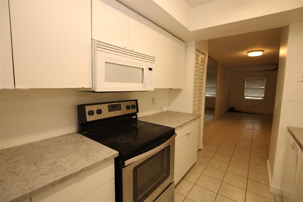 A kitchen features white cabinets, a stainless steel stove, and light-colored countertops — 53 W MARBRISA WAY, KISSIMMEE, FL