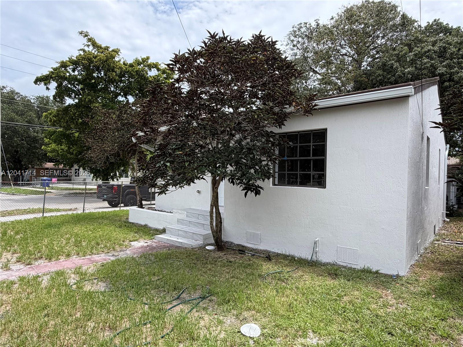A white house exterior features a dark-leafed tree in the front yard and tiled steps — 7675 NW 3rd Ave # 1, Miami FL 33150, MIAMI, FL