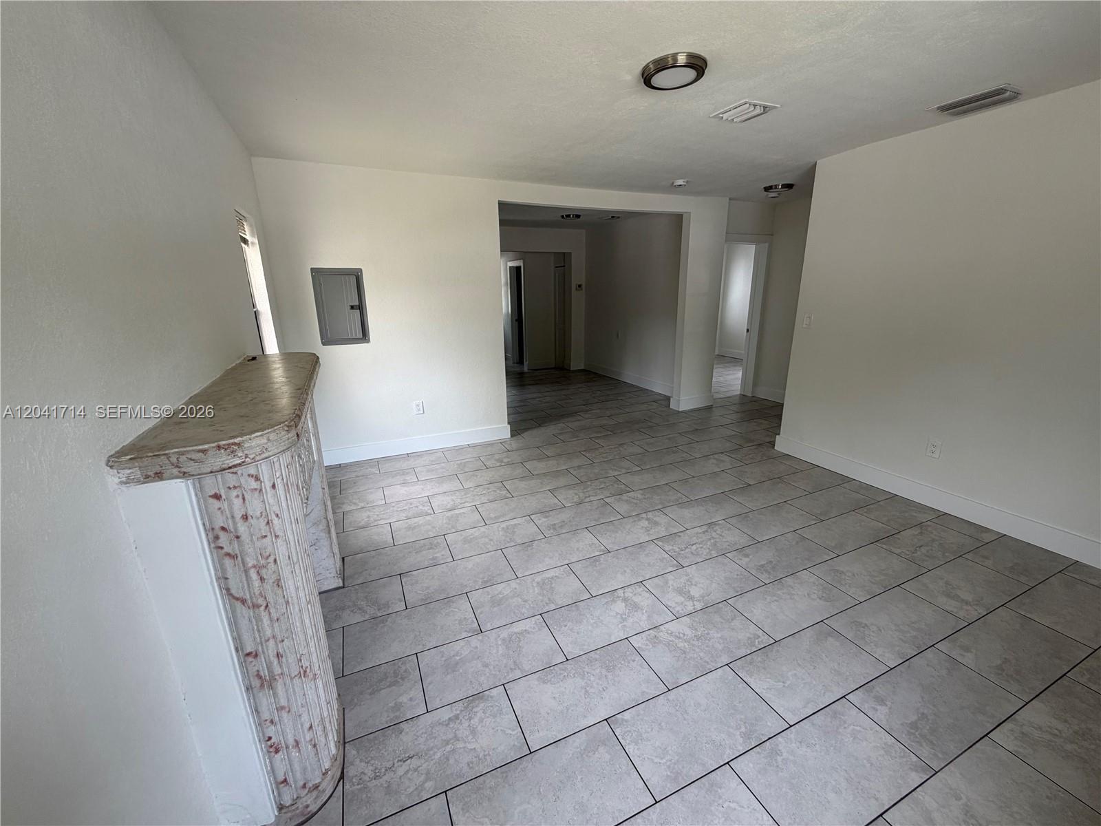 An interior room features light-colored tile flooring, white walls, and a decorative fireplace mantel — 7675 NW 3rd Ave # 1, Miami FL 33150, MIAMI, FL