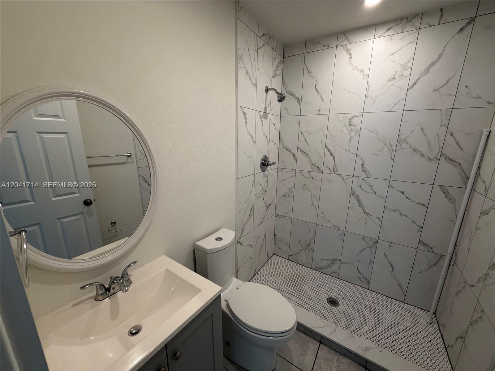 A bathroom features a vanity with a round mirror, a toilet, and a tiled shower — 7675 NW 3rd Ave # 1, Miami FL 33150, MIAMI, FL