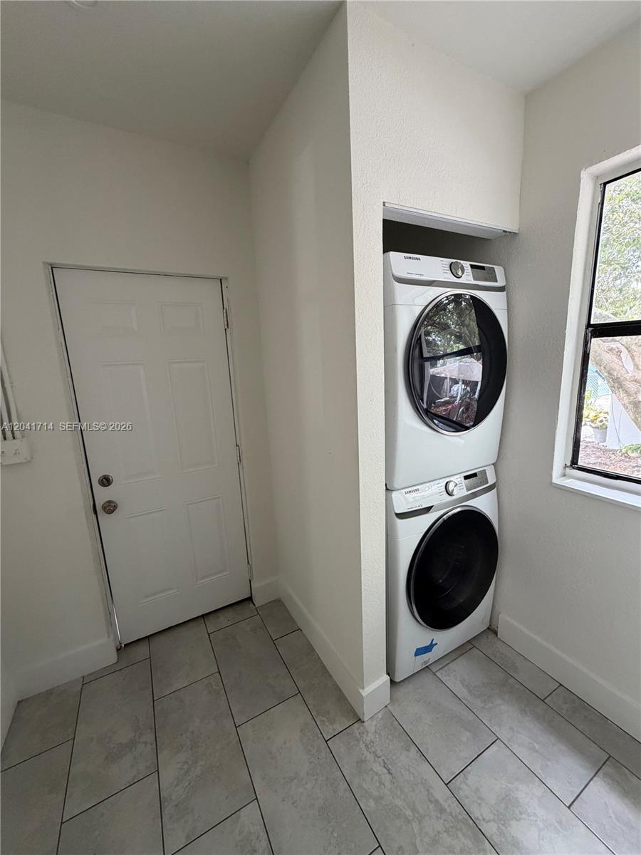 A laundry room features a stacked washer and dryer set next to a white door — 7675 NW 3rd Ave # 1, Miami FL 33150, MIAMI, FL