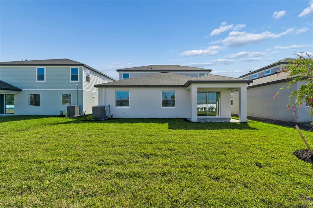The rear exterior of a single-story house features a covered patio and a grassy yard — 4710 OUTHAUL RUN, PALMETTO, FL
