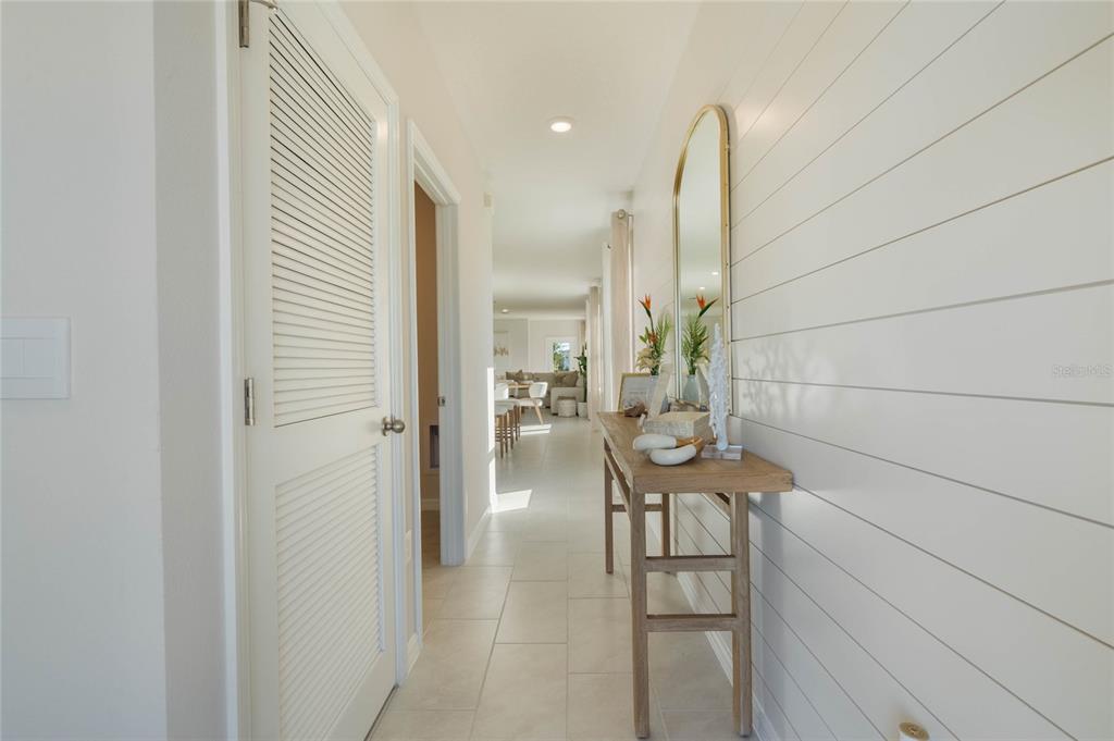 A hallway with white shiplap walls, a wooden console table, and a louvered door — 3023 VICEROY, POINCIANA, FL