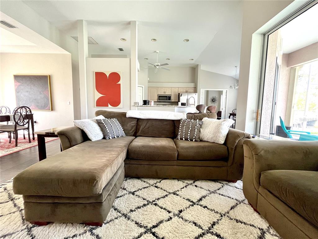A living room features a brown sectional sofa on a white patterned rug — 1268 W HILLSBOROUGH BOULEVARD, NORTH PORT, FL