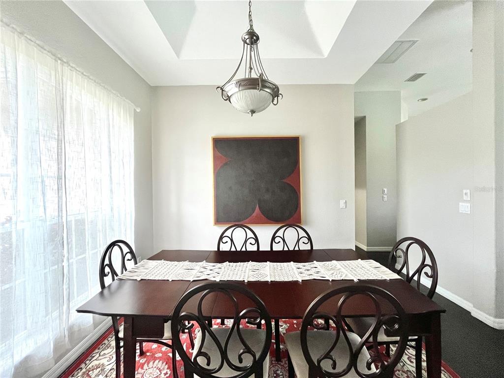 A dining room features a dark wood table, scroll-back chairs, a chandelier, and abstract art — 1268 W HILLSBOROUGH BOULEVARD, NORTH PORT, FL