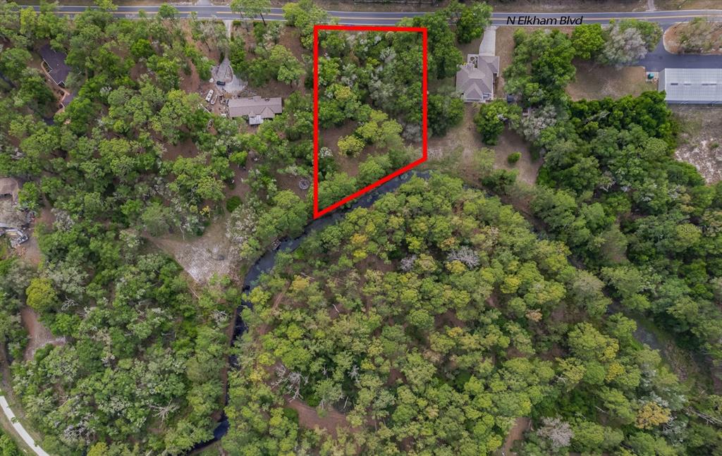 An aerial view shows a wooded lot outlined in red bordering a small creek — 12205 N ELKCAM BOULEVARD, DUNNELLON, FL