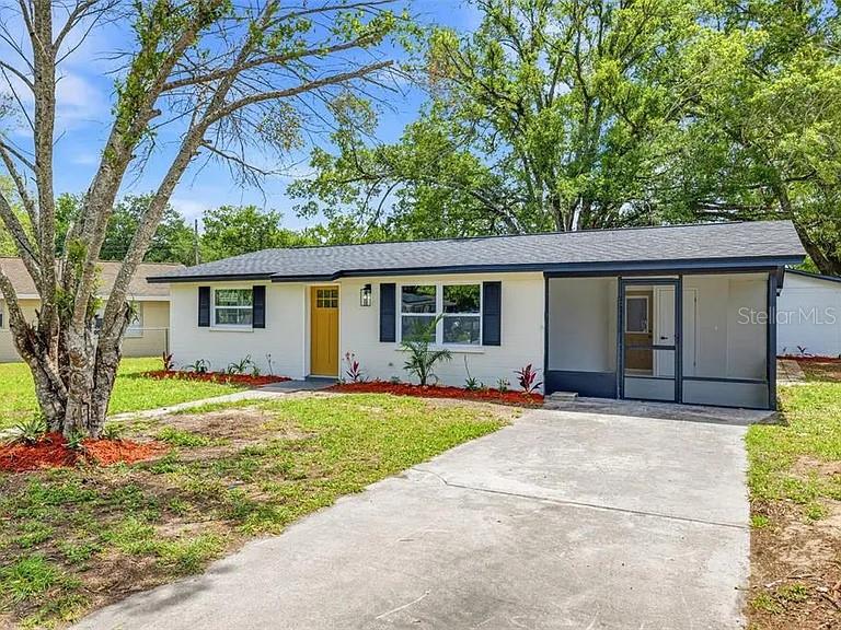 A single-story house with a white exterior, yellow front door, and an attached screened porch — 39252 HEIGHTS AVENUE, ZEPHYRHILLS, FL