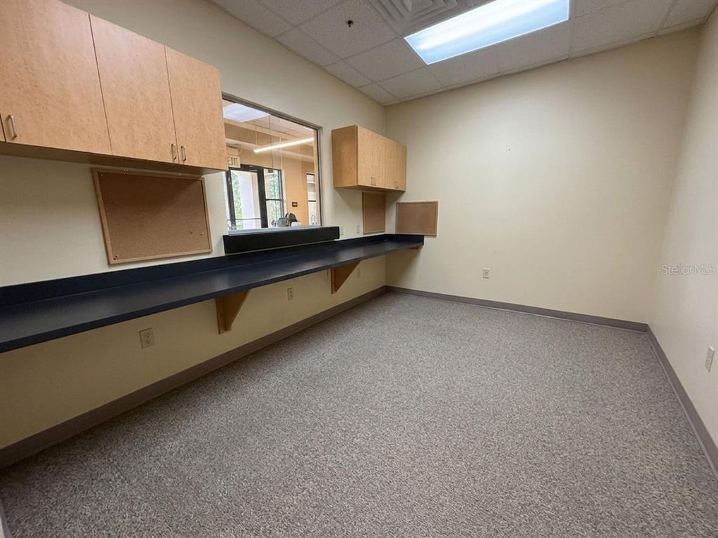 An office room features a long dark countertop, light wood cabinets, and beige carpet flooring — 578 OCOEE COMMERCE PARKWAY, OCOEE, FL