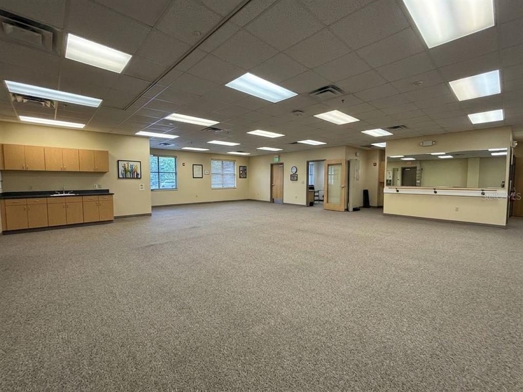 A large, carpeted multipurpose room features a kitchenette, mirrored wall, and recessed ceiling lighting — 578 OCOEE COMMERCE PARKWAY, OCOEE, FL