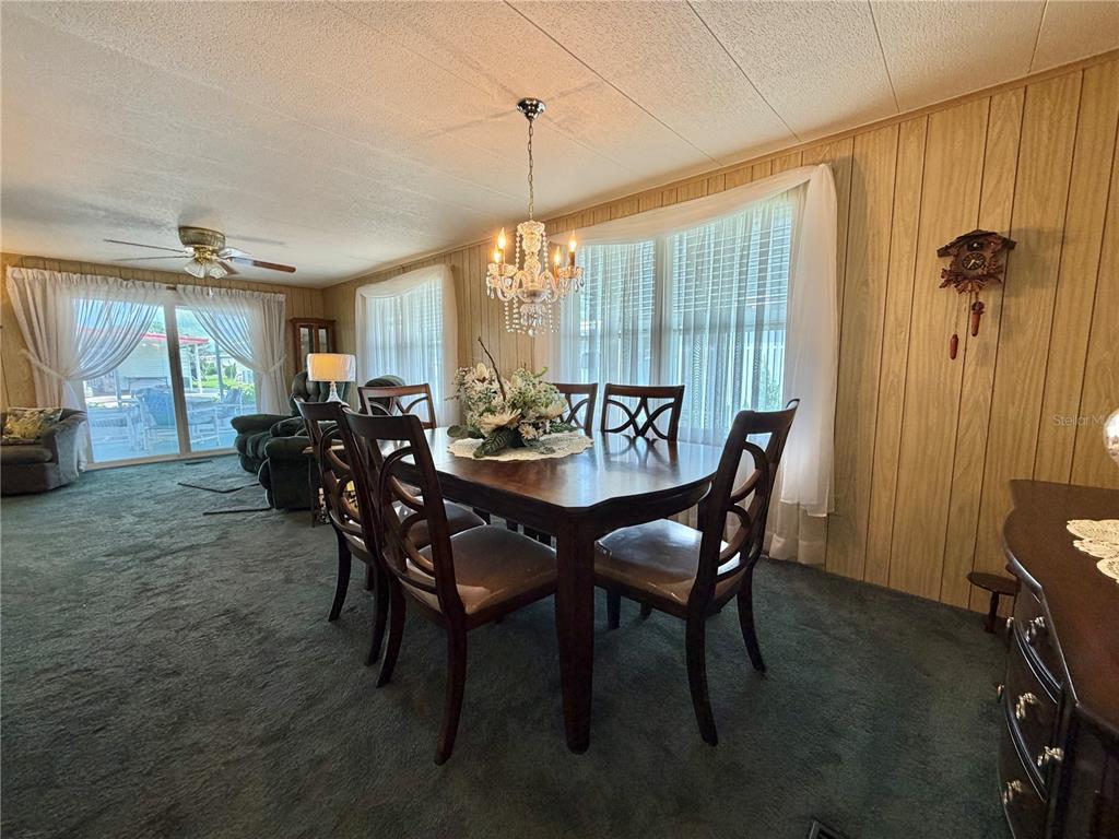 A dining room features a wooden table, six chairs, a crystal chandelier, and wood-paneled walls — 100 MARIGOLD STREET, LEESBURG, FL