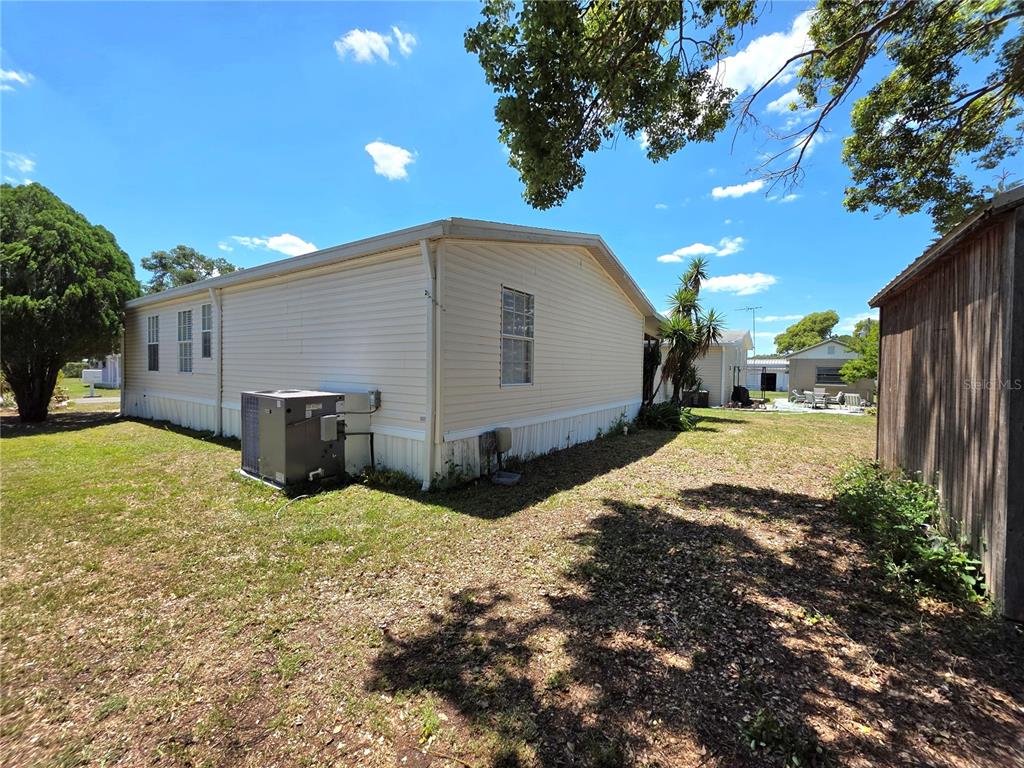 The exterior of a light-colored mobile home features a central air conditioning unit — 37251 LOIS AVENUE, ZEPHYRHILLS, FL