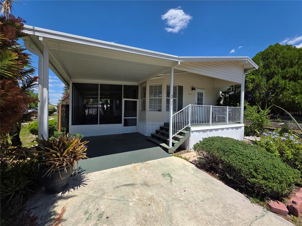 A mobile home features a screened-in carport, a front porch with stairs, and a concrete driveway — 37251 LOIS AVENUE, ZEPHYRHILLS, FL