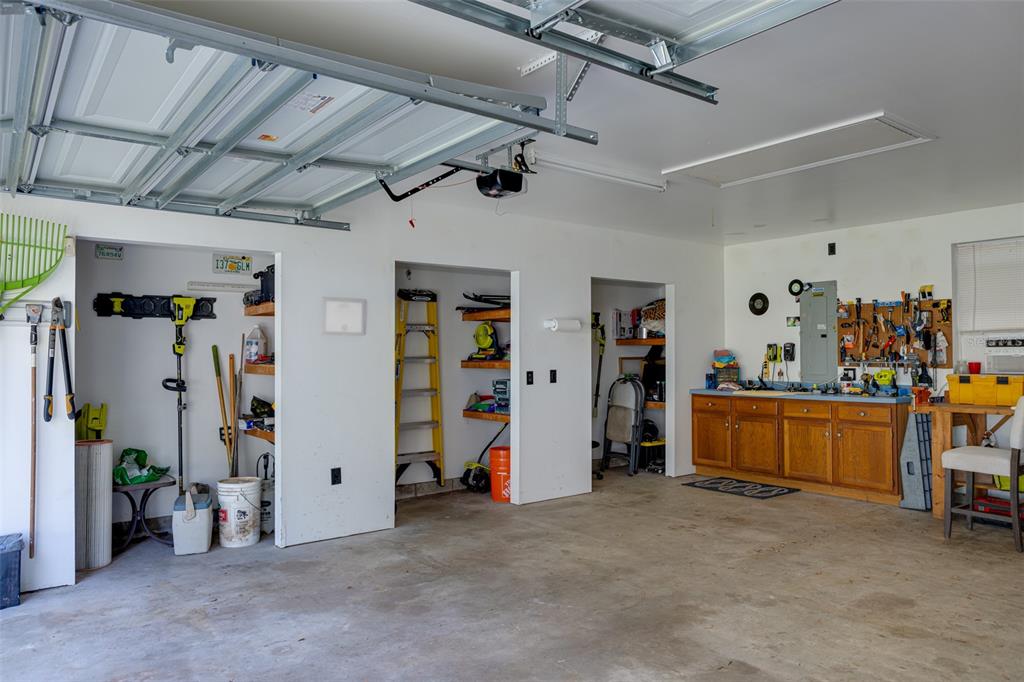 A garage with concrete floors, storage alcoves, a workbench, and a ceiling-mounted garage door opener — 39 WOOD RIDGE DRIVE, OCALA, FL