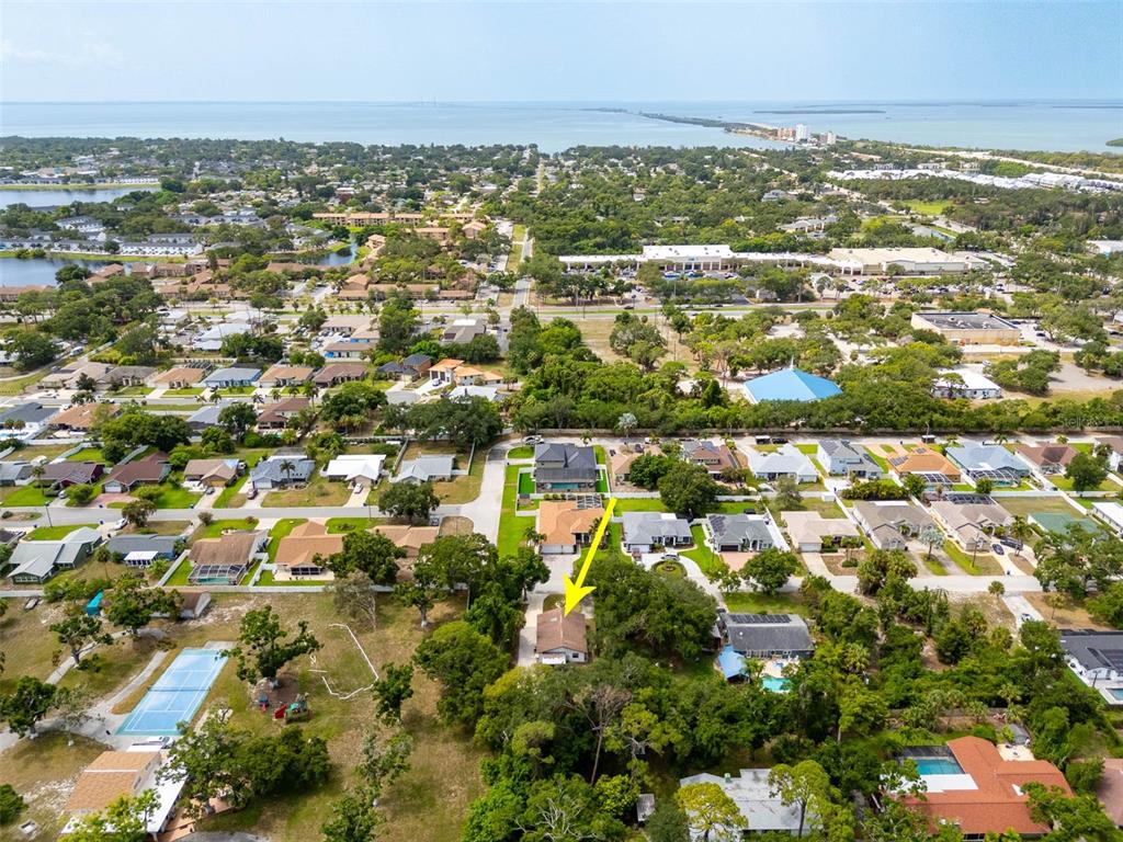 A white, single-story house with a slanted roof sits behind a circular front yard garden — 2801 51ST AVENUE S, ST PETERSBURG, FL