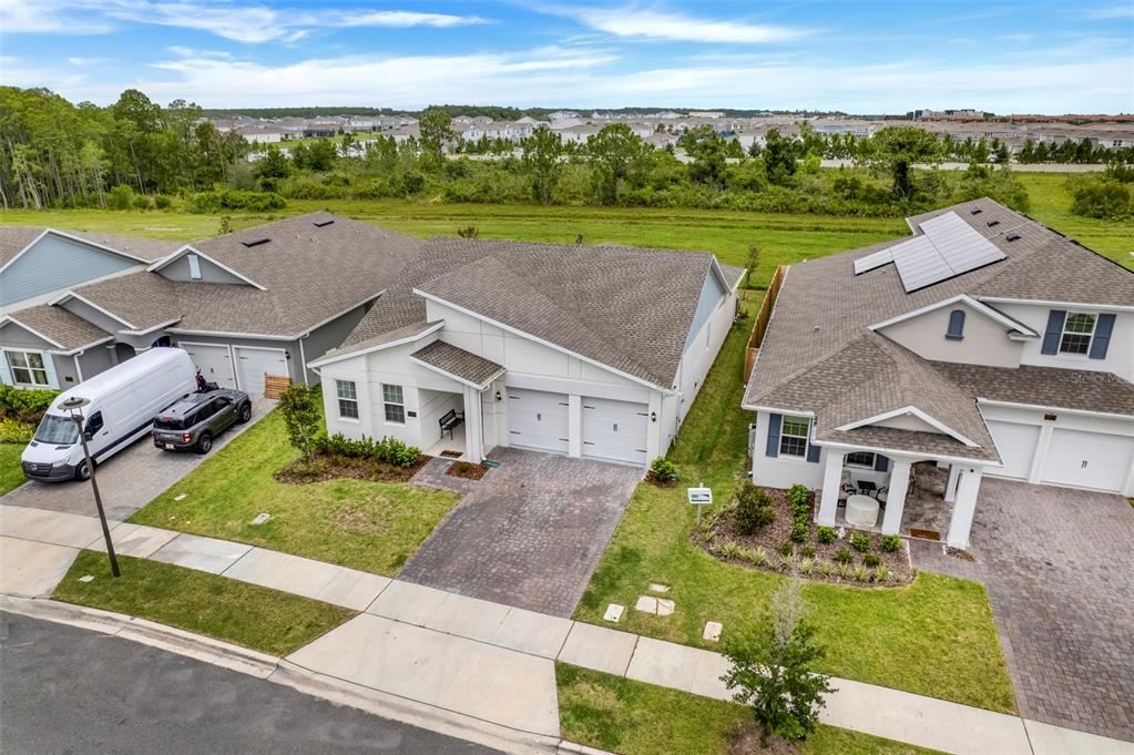 An aerial view shows three suburban houses with paved driveways and green lawns — 18863 RAWSON STREET, ORLANDO, FL