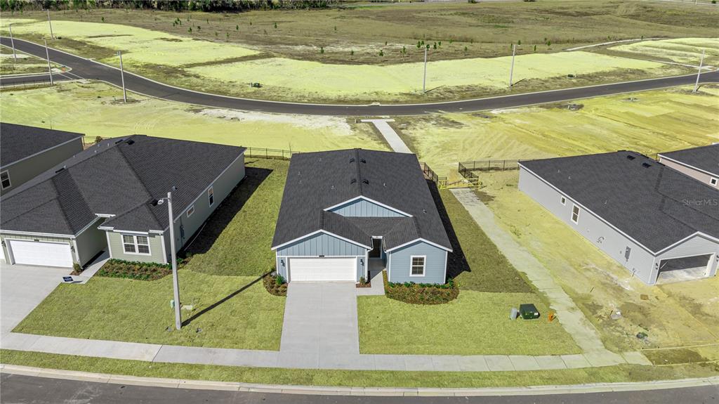 An aerial view shows a blue single-story house with a dark roof and concrete driveway — 14358 NW CONVERGENCE BOULEVARD, ALACHUA, FL