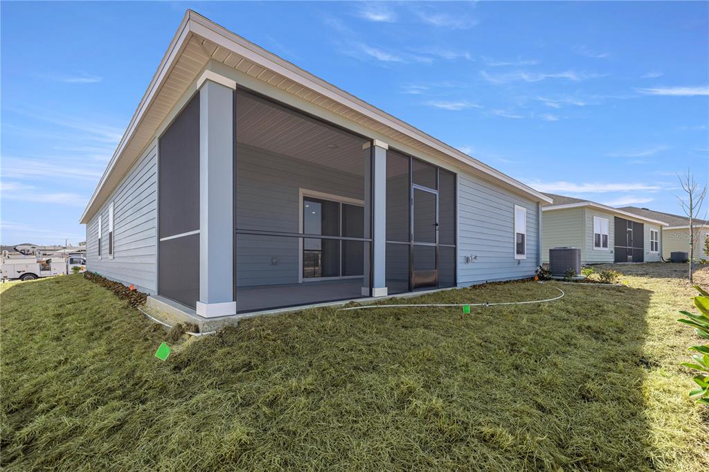 The exterior of a light blue house features a screened-in porch and a grassy yard — 14358 NW CONVERGENCE BOULEVARD, ALACHUA, FL