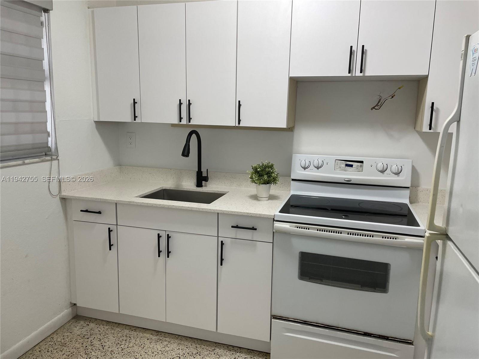 A kitchen features white cabinets, a black faucet, a stainless steel sink, and white appliances — 142 SW 18th Ave # 19, Miami FL 33135, MIAMI, FL