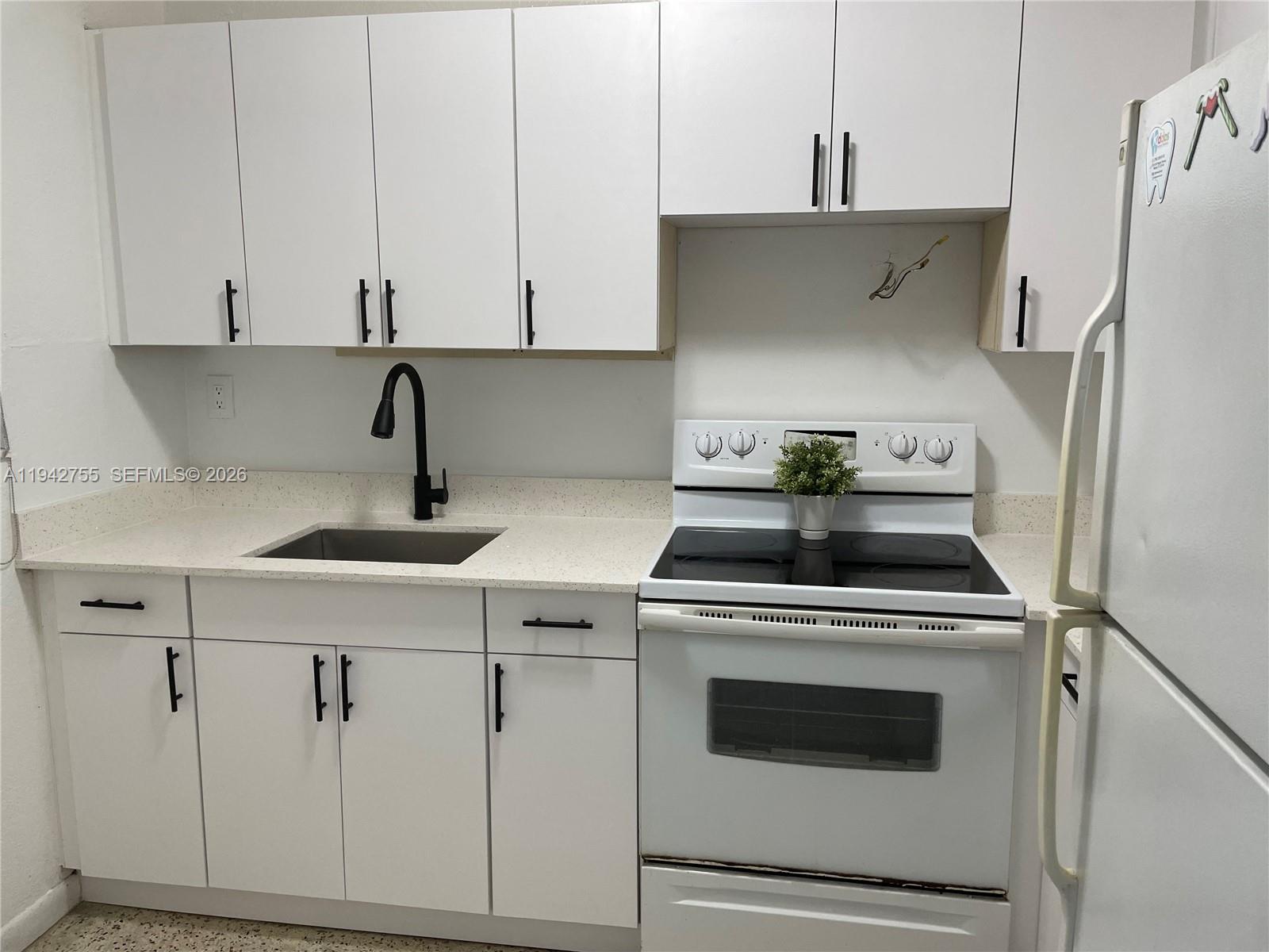 A kitchen features white cabinets, a speckled countertop, a black faucet, and white appliances — 142 SW 18th Ave # 19, Miami FL 33135, MIAMI, FL