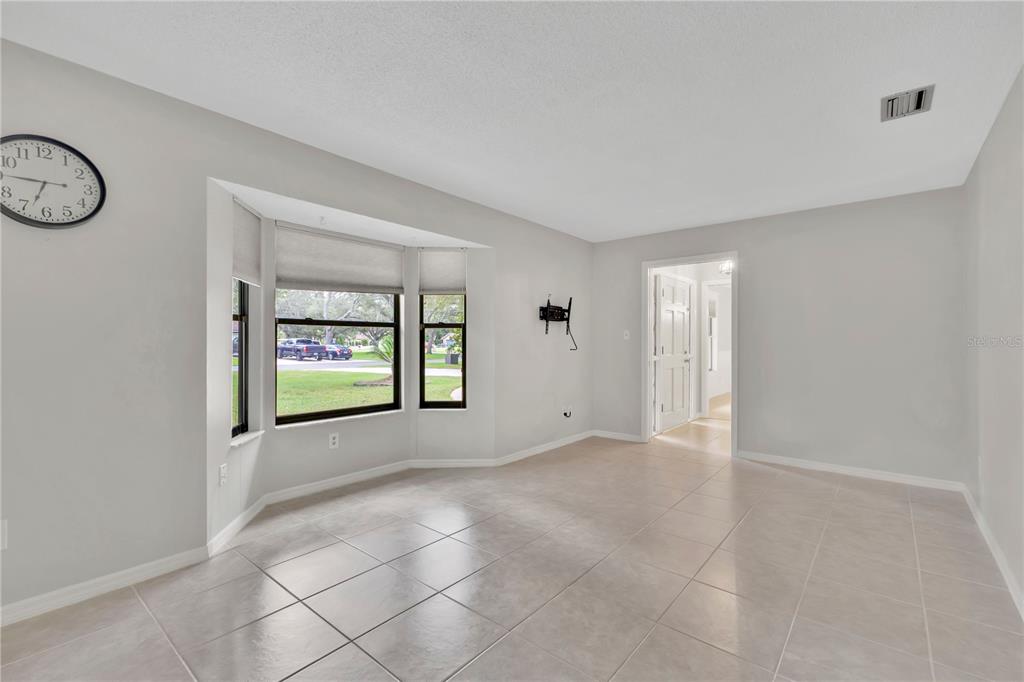 A bright room features light-colored tile flooring, a bay window, and a wall-mounted television bracket — 3292 MAJESTIC OAK DRIVE, ST CLOUD, FL