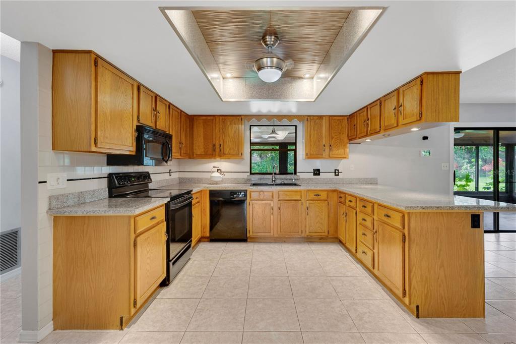 A kitchen with oak cabinets, granite countertops, tile flooring, and a recessed ceiling light fixture — 3292 MAJESTIC OAK DRIVE, ST CLOUD, FL