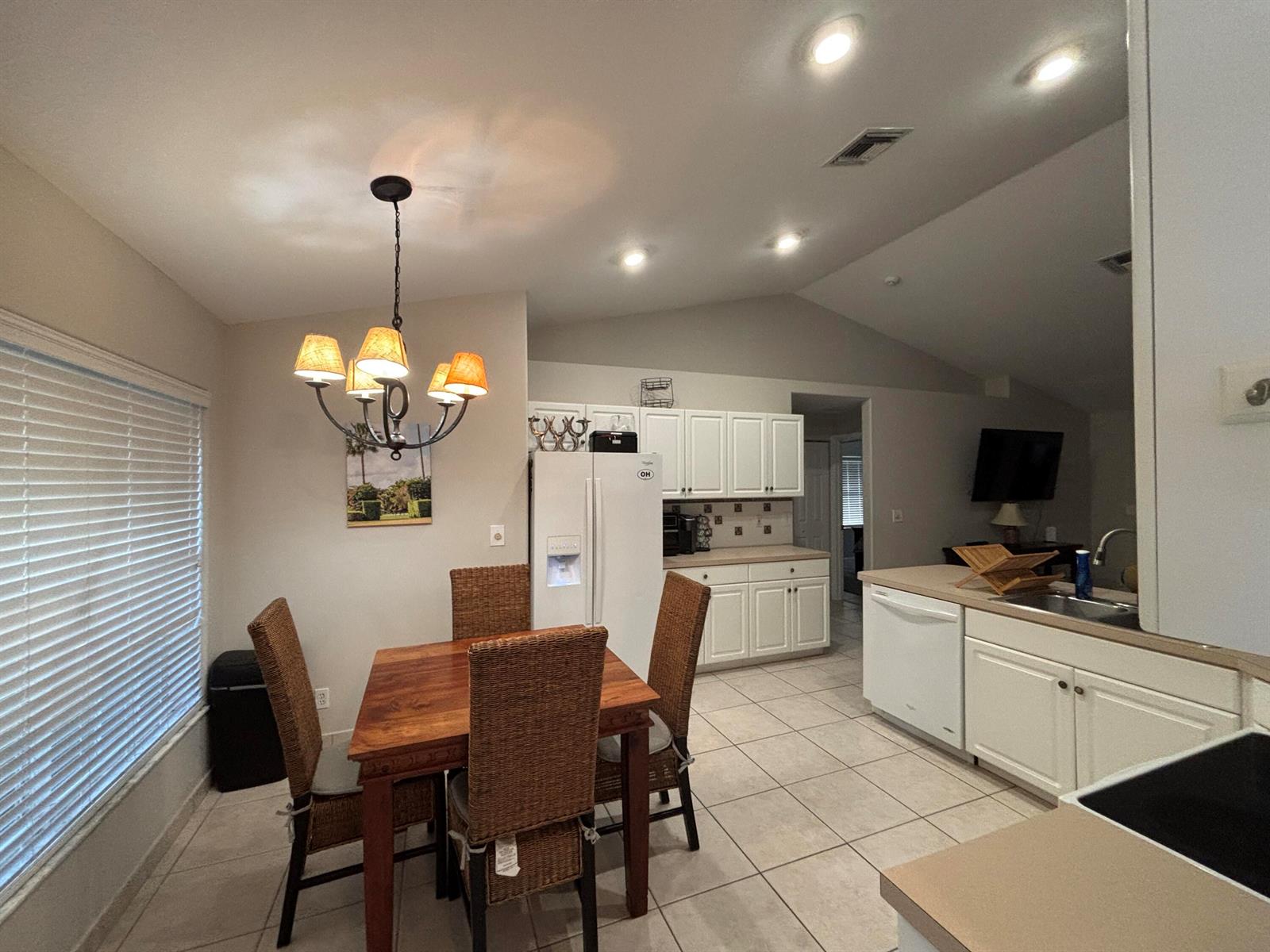 A kitchen and dining area with white cabinets, tile floors, and a wooden dining set — 1094 Raintree Lane, Wellington FL 33414, WELLINGTON, FL