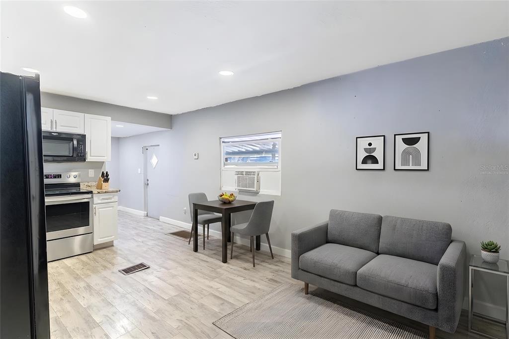 A small, open-concept room features a kitchen area, a dining table, and a gray sofa — 5807 BARRY LANE, TAMPA, FL
