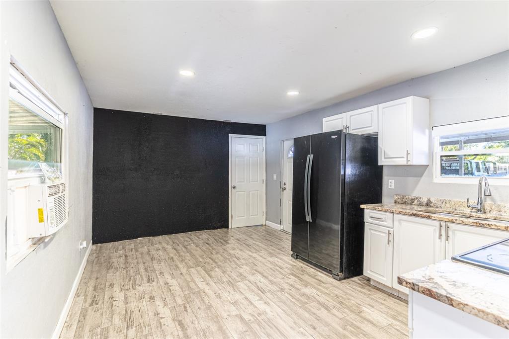 A kitchen features white cabinets, granite countertops, a black refrigerator, and a black accent wall — 5807 BARRY LANE, TAMPA, FL