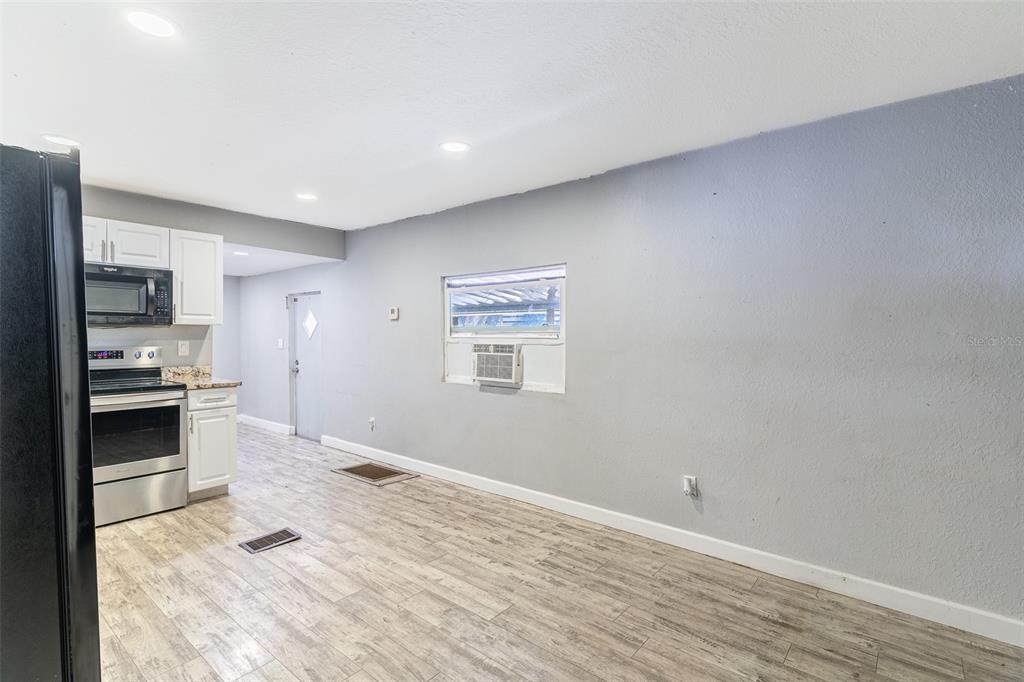 A kitchen with white cabinets and stainless steel appliances opens into a gray-walled living area — 5807 BARRY LANE, TAMPA, FL