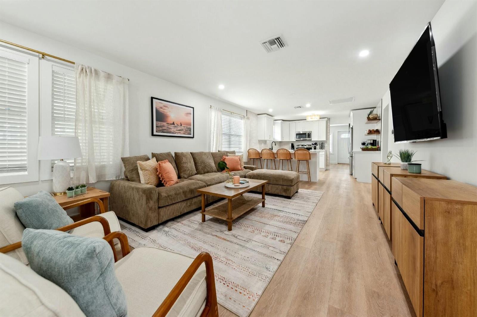 A living room with a brown sectional, two armchairs, and an open kitchen with bar seating — 125 NW 3rd Avenue, Delray Beach FL 33444, DELRAY BEACH, FL